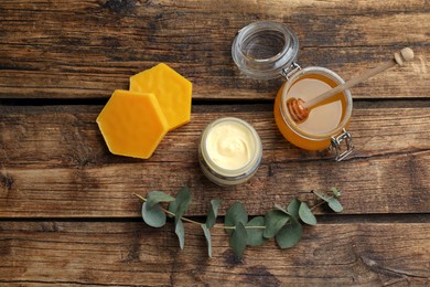 Natural beeswax, cream, honey and eucalyptus on wooden table, flat lay