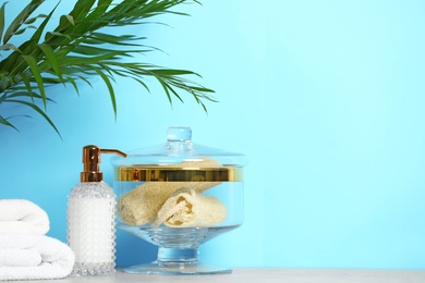Composition of glass jar with luffa sponges on table near blue wall. Space for text