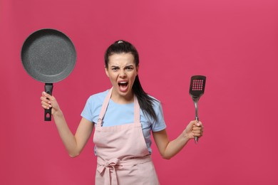 Photo of Emotional housewife with frying pan and spatula on pink background