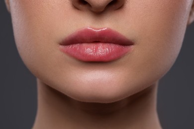 Photo of Young woman with beautiful lips on grey background, closeup