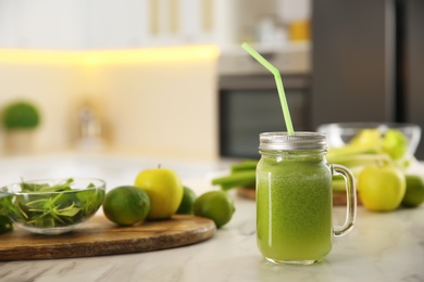 Photo of Tasty fresh juice with straw in mason jar on table indoors. Space for text
