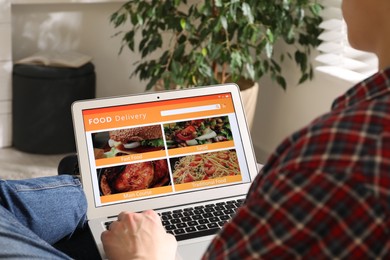 Man using laptop for ordering food online at home, closeup. Delivery service
