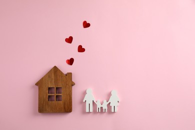 Figures of family, house and red hearts on pink background, flat lay. Space for text