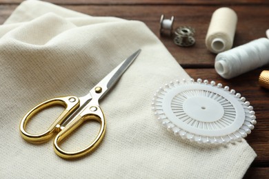 Photo of Different sewing supplies on wooden table, closeup