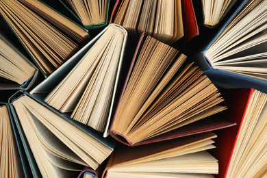Photo of Many different hardcover books on dark background, top view
