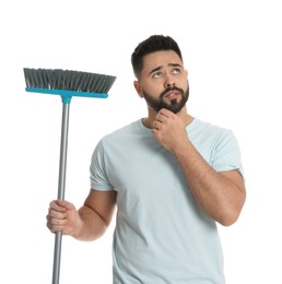 Thoughtful young man with broom on white background