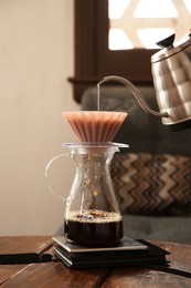 Photo of Preparing coffee at wooden table in cafe, closeup