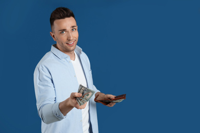 Photo of Happy man with cash money and wallet on blue background. Space for text
