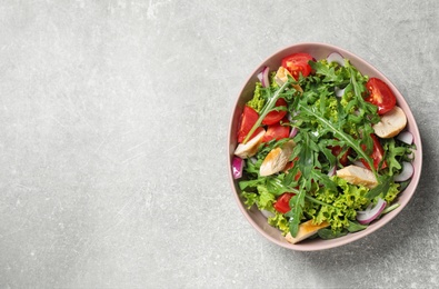 Delicious salad with chicken, arugula and tomatoes on grey table, top view. Space for text