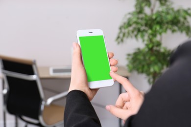 Image of Woman using smartphone with green screen indoors, closeup. Gadget display with chroma key. Mockup for design