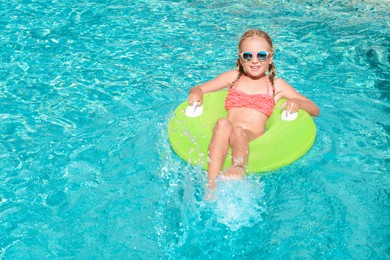 Cute little girl with inflatable ring in pool on sunny day. space for text