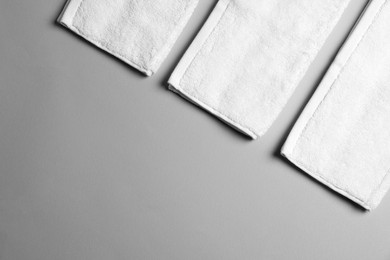 Soft folded white towels on light grey background, flat lay. Space for text