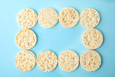 Frame made of puffed rice cakes on light blue background, flat lay. Space for text