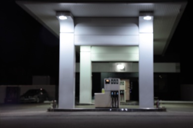 Blurred view of modern gas station with convenience store beside the road at night