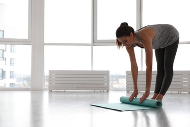 Young woman unrolling mat in yoga studio