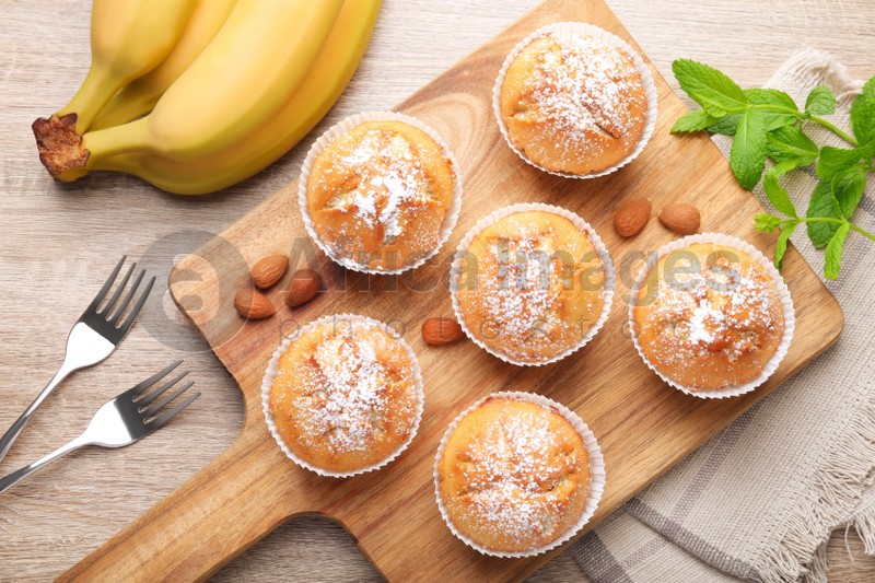Photo of Flat lay composition with tasty banana muffins on wooden table
