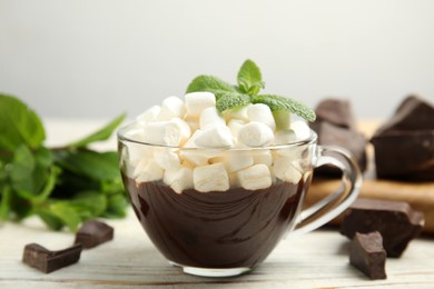 Glass cup of delicious hot chocolate with marshmallows and fresh mint on white wooden table