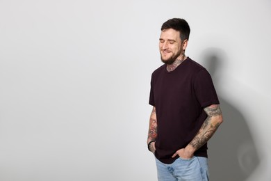 Photo of Smiling hipster man on light grey background. Space for text
