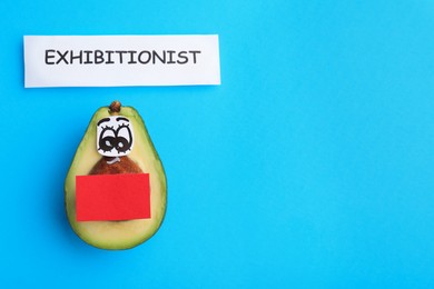 Photo of Avocado with drawn face and word exhibitionist on light blue background, flat lay. Space for text