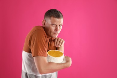 Greedy man hiding tasty cake on pink background. Space for text