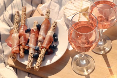 Glasses of delicious rose wine and food on white picnic blanket