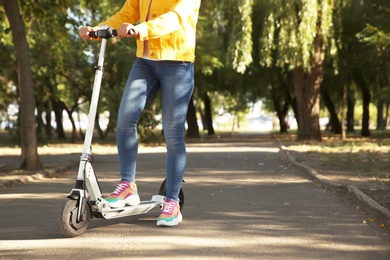 Woman riding electric kick scooter outdoors. Space for text