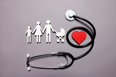 Photo of Figures of family near stethoscope and heart on lilac background, top view. Insurance concept