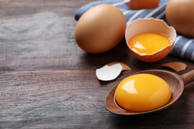 Spoon with raw egg yolk on wooden table, closeup. Space for text