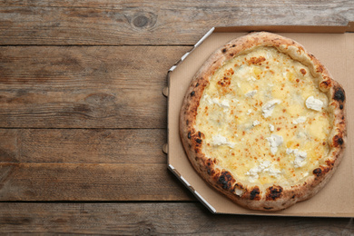 Photo of Delicious cheese pizza in takeout box on wooden table, top view. Space for text