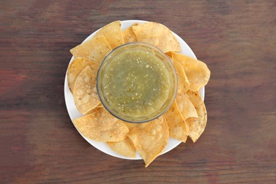 Photo of Tasty salsa sauce and tortilla chips on wooden table, top view