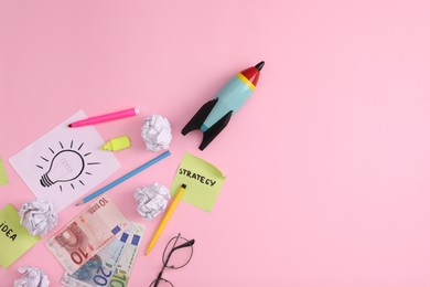 Flat lay composition with stationery, money and toy rocket on pink background, space for text. Startup concept