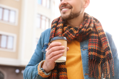 Man with cup of coffee on city street in morning, closeup