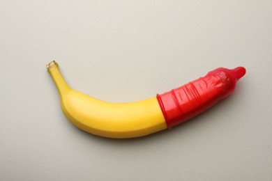 Banana with condom on light grey background, top view. Safe sex concept