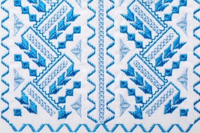 Beautiful light blue Ukrainian national embroidery on white fabric, top view