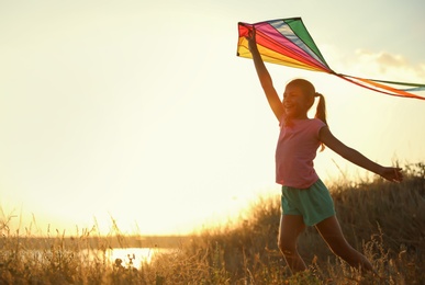 Cute little child with kite running outdoors at sunset. Spending time in nature
