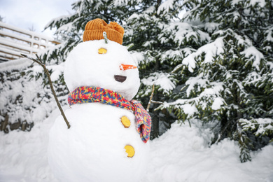 Funny snowman with hat and scarf outdoors. Winter vacation