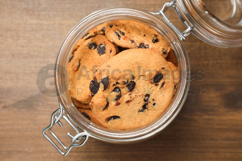 Jar of chocolate chip cookies on wooden table, top view