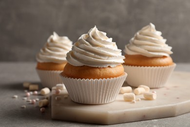 Delicious cupcakes decorated with cream on light grey table