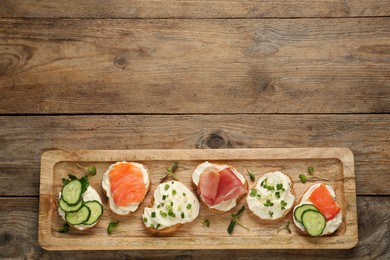 Photo of Delicious sandwiches with cream cheese and other ingredients on wooden table, top view. Space for text