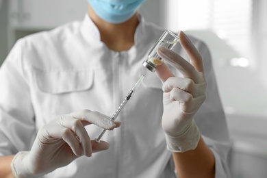 Doctor filling syringe with medication in clinic, closeup. Vaccination and immunization