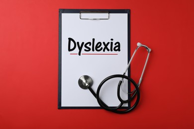Image of Clipboard with word Dyslexia and stethoscope on red background, top view