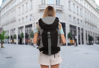 Traveler with backpack in foreign city during summer vacation, back view