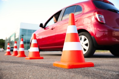 Photo of Traffic cones near red car outdoors. Driving school exam
