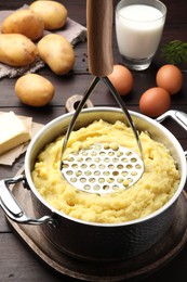 Photo of Mashing potatoes in pot on wooden table