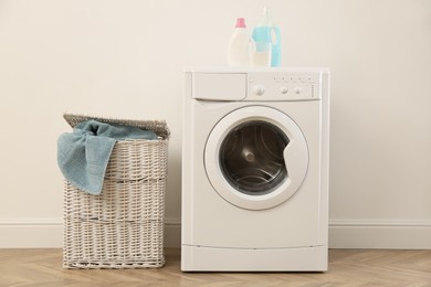 Laundry room interior with modern washing machine and wicker basket near white wall