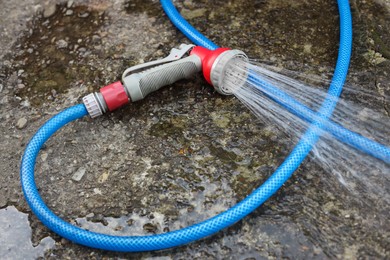 Water spraying from hose on stone surface outdoors