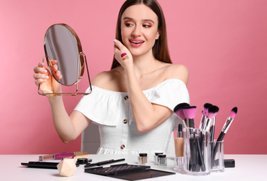 Beauty blogger with mirror on pink background