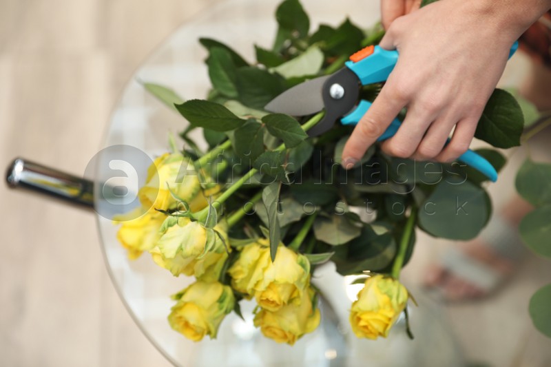 Female florist making beautiful bouquet in flower shop, top view