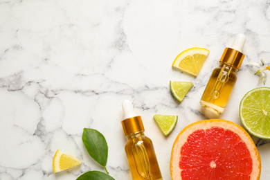 Flat lay composition with bottles of citrus essential oil on white marble background. Space for text