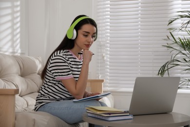 Young woman watching webinar on sofa at home
